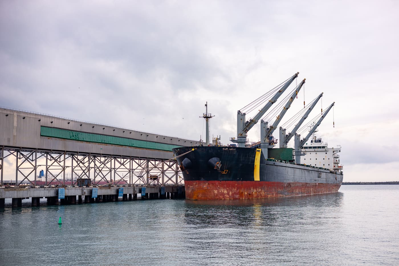 A bulk vessel alongside a jetty with a conveyor gantry running out over the water